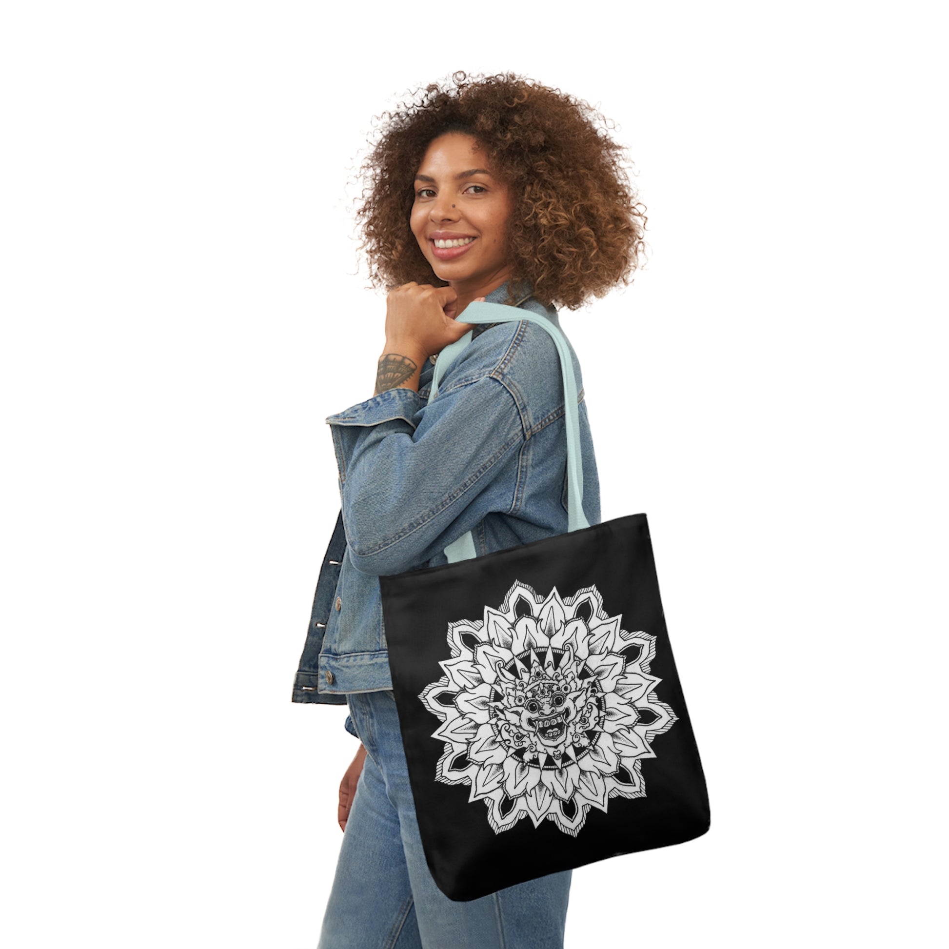 smiling woman holding black mandalarian brand tote bag with light blue handle and bhoma bali god design print on both sides