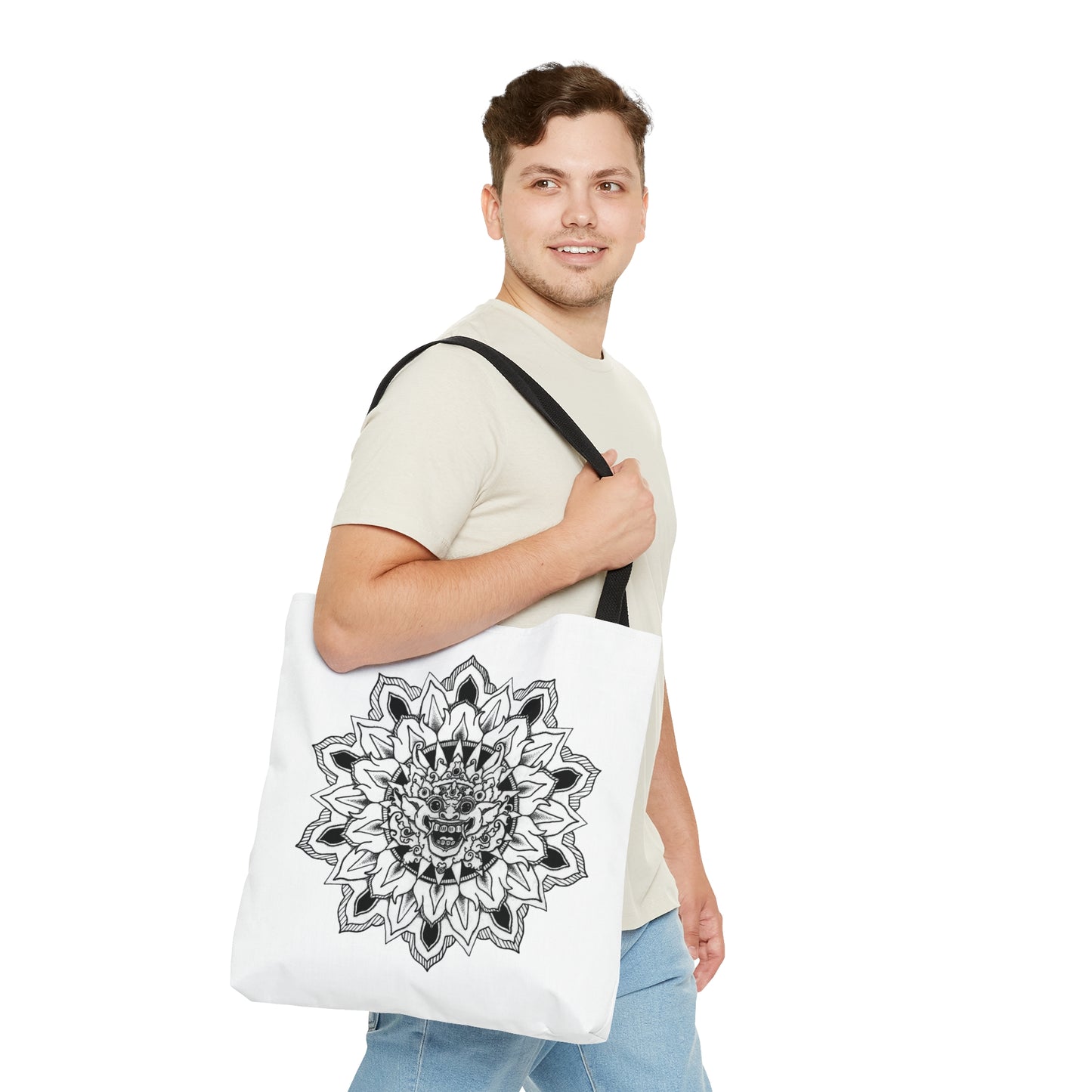 man smiling holding white mandalarian brand tote bag with black handle and black and white bhoma bali god mandala design print on both sides