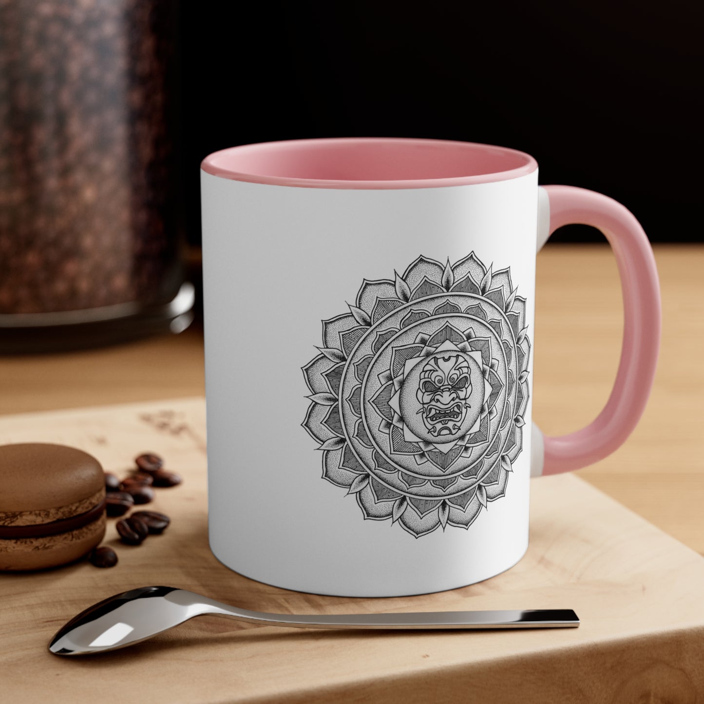 a two toned white and pink 11oz coffee mug on a table with a samurai mask mandala design