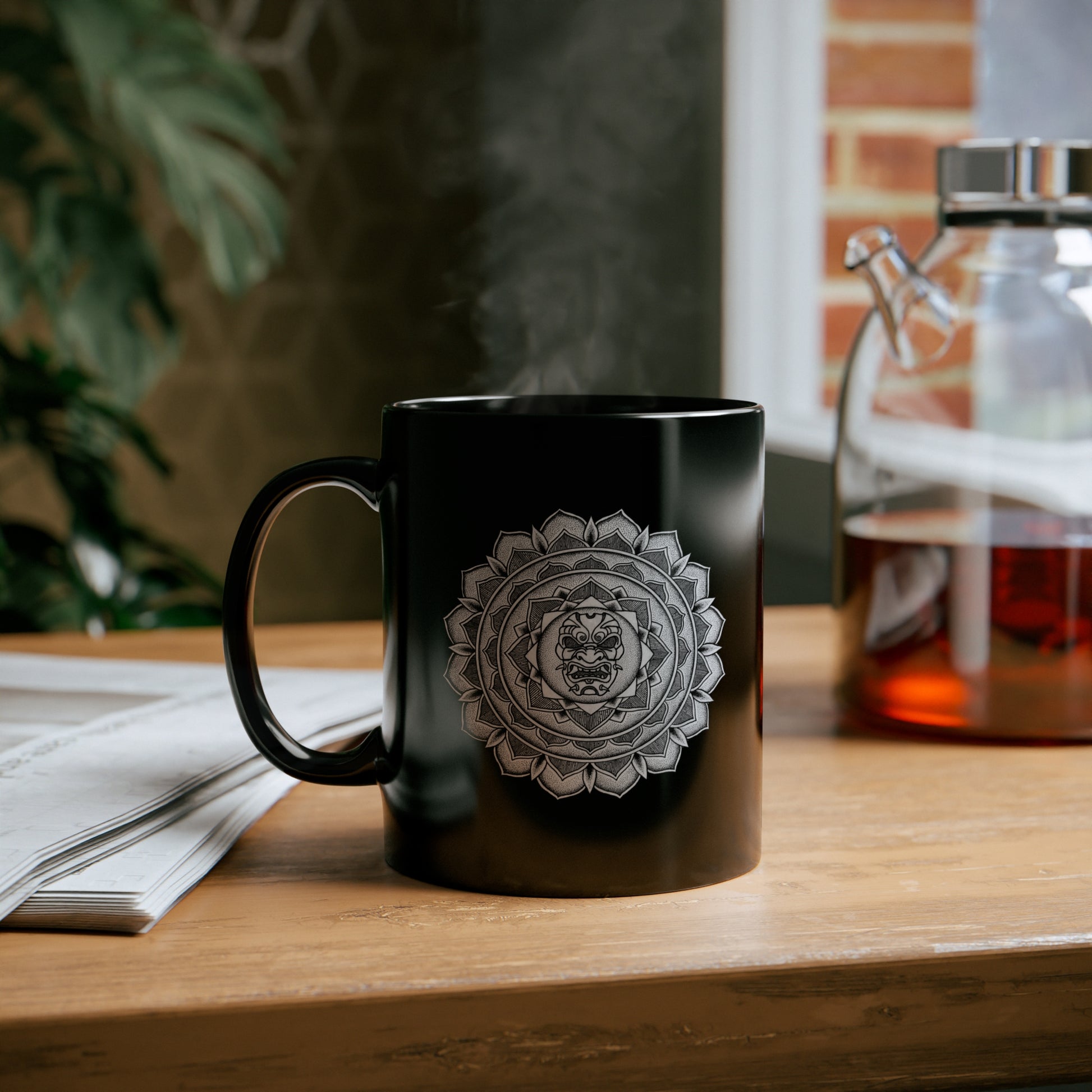  black 11oz coffee mug with white samurai mask mandala design on a table