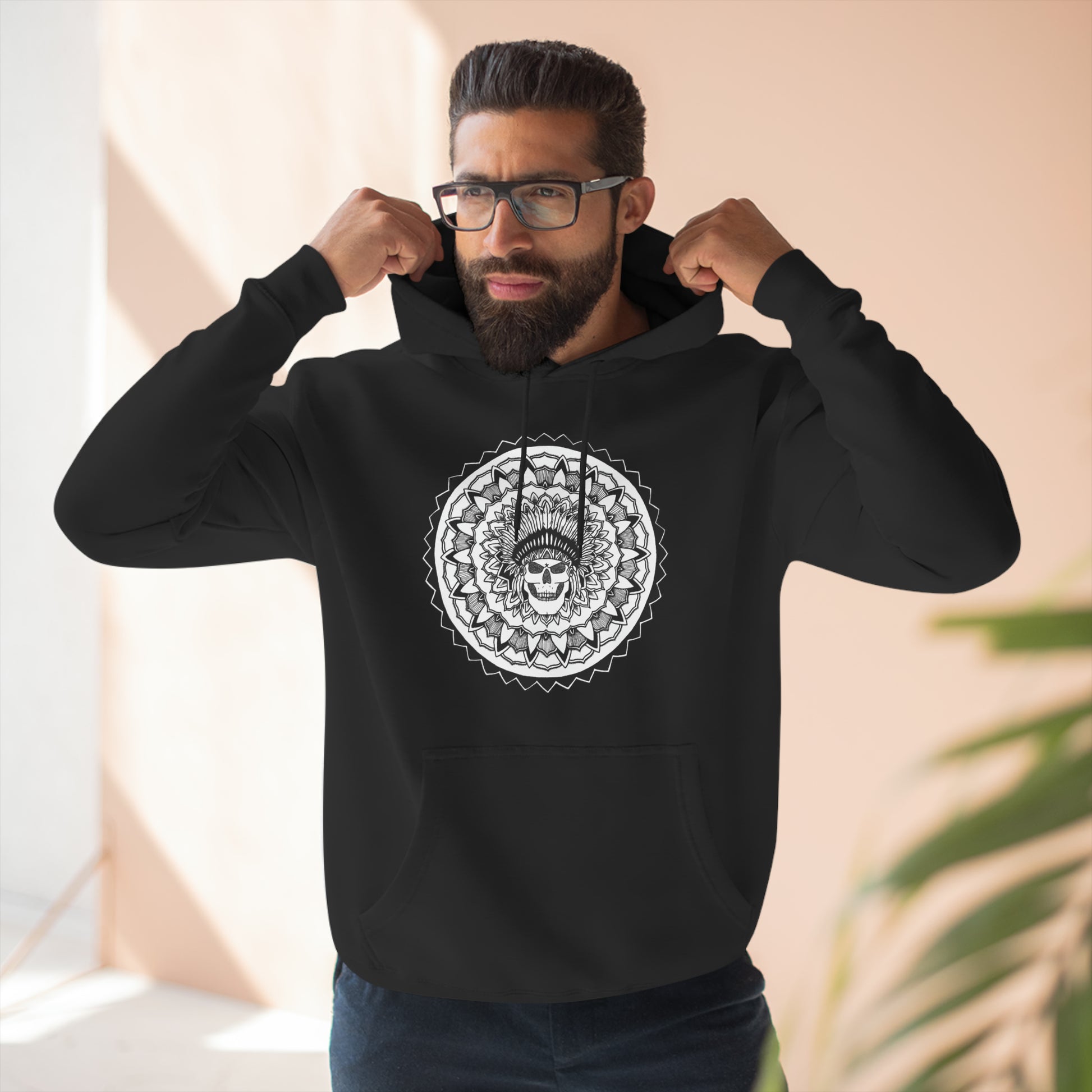 man wearing glasses and a black mandalarian brand hoodie with chieftain skull tattoo design mandala on front