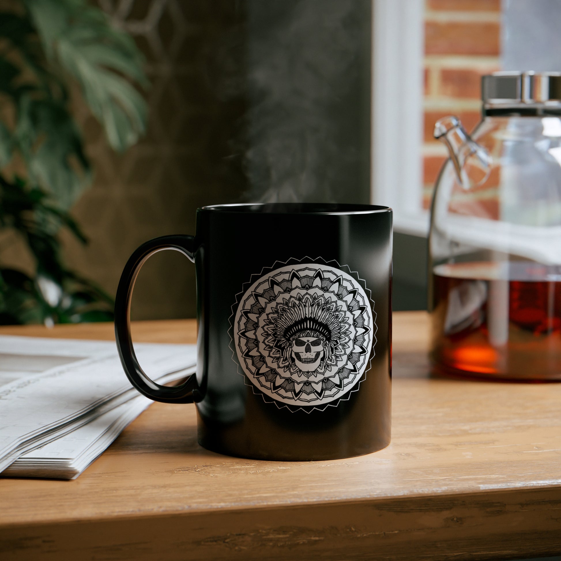 a black 11oz coffee mug with white chieftain skull mandala design on a table