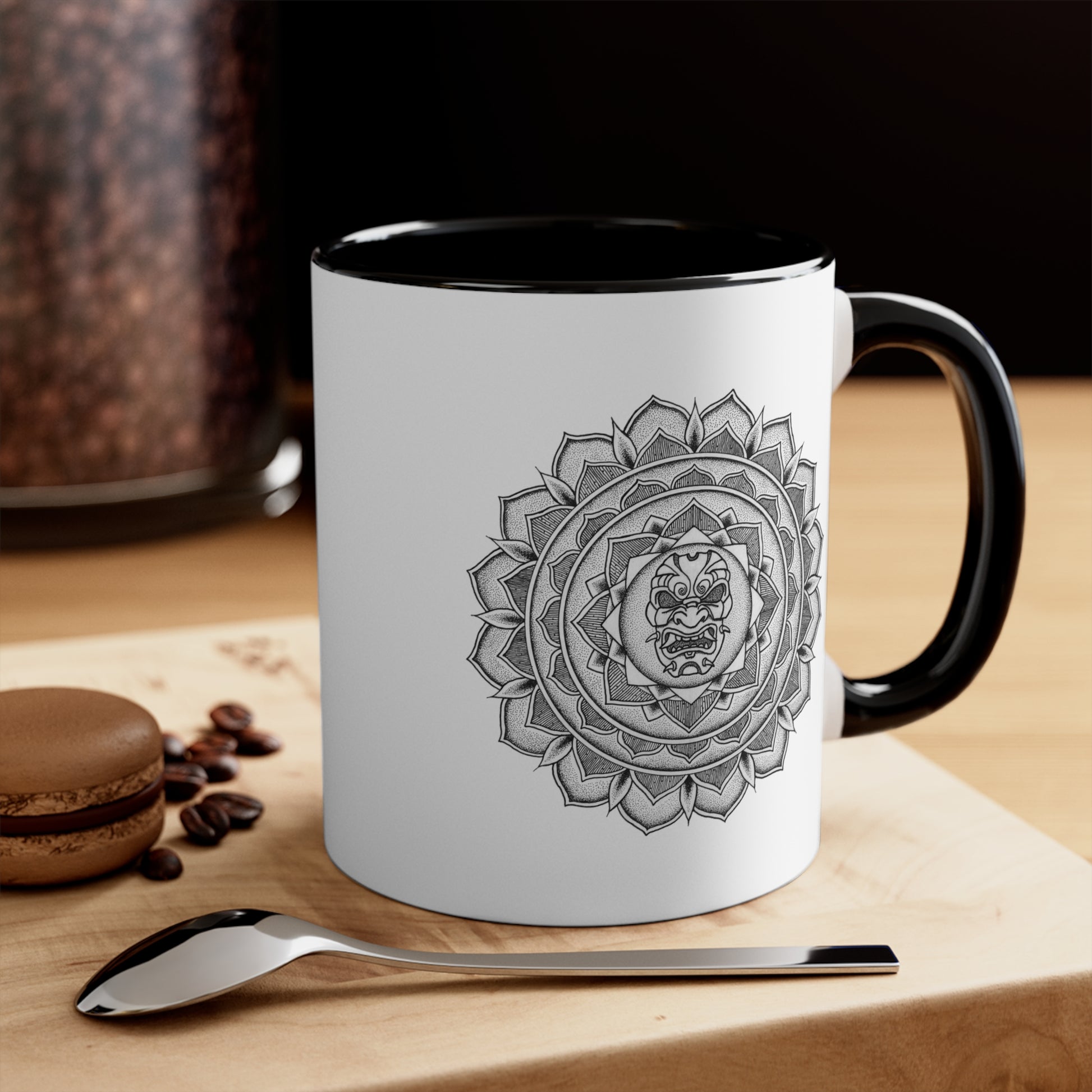 two toned black and white 11oz coffee mug on a table with a samurai mask mandala design