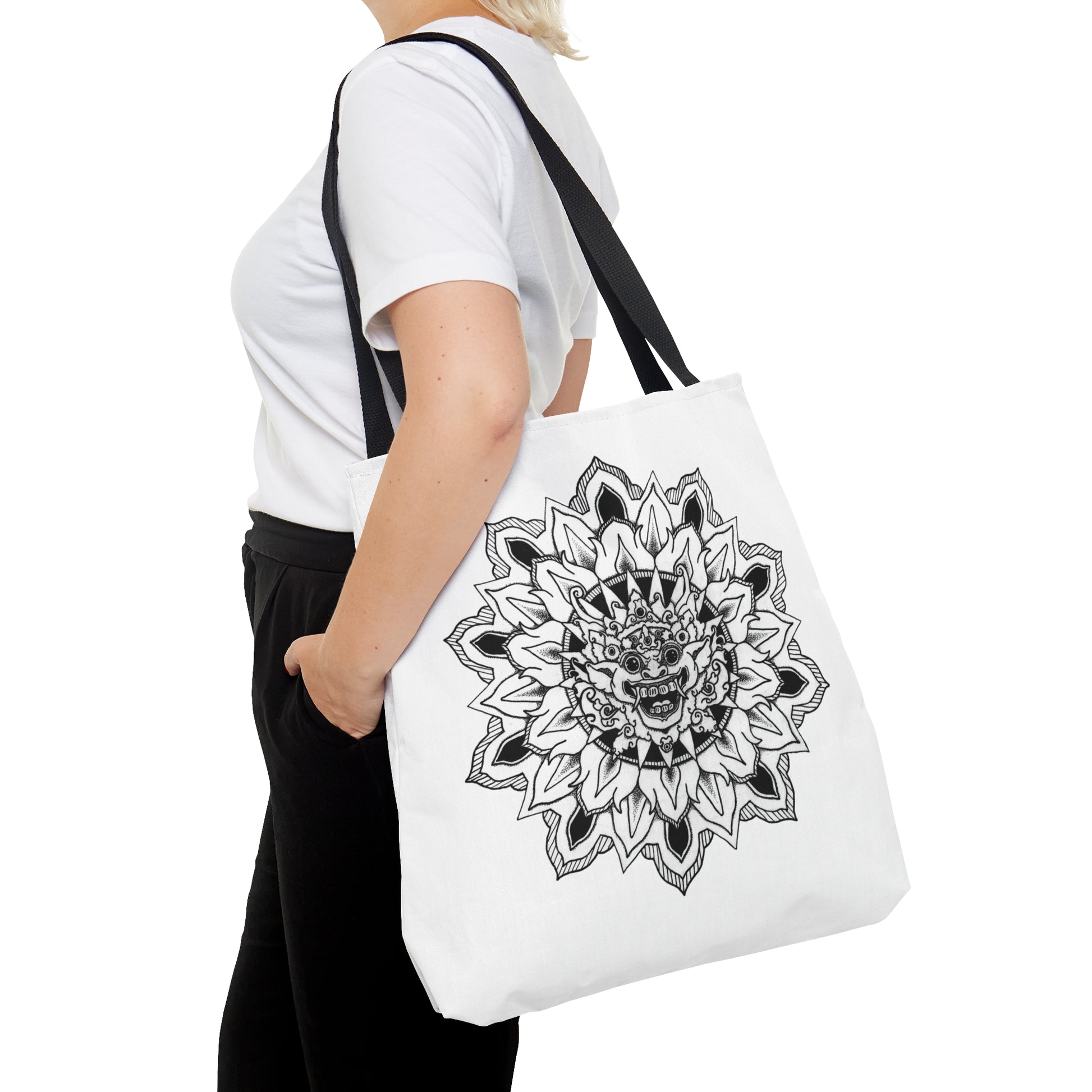 a woman smiling holding white mandalarian brand tote bag with black handle and black and white bhoma bali god mandala design print on both sides