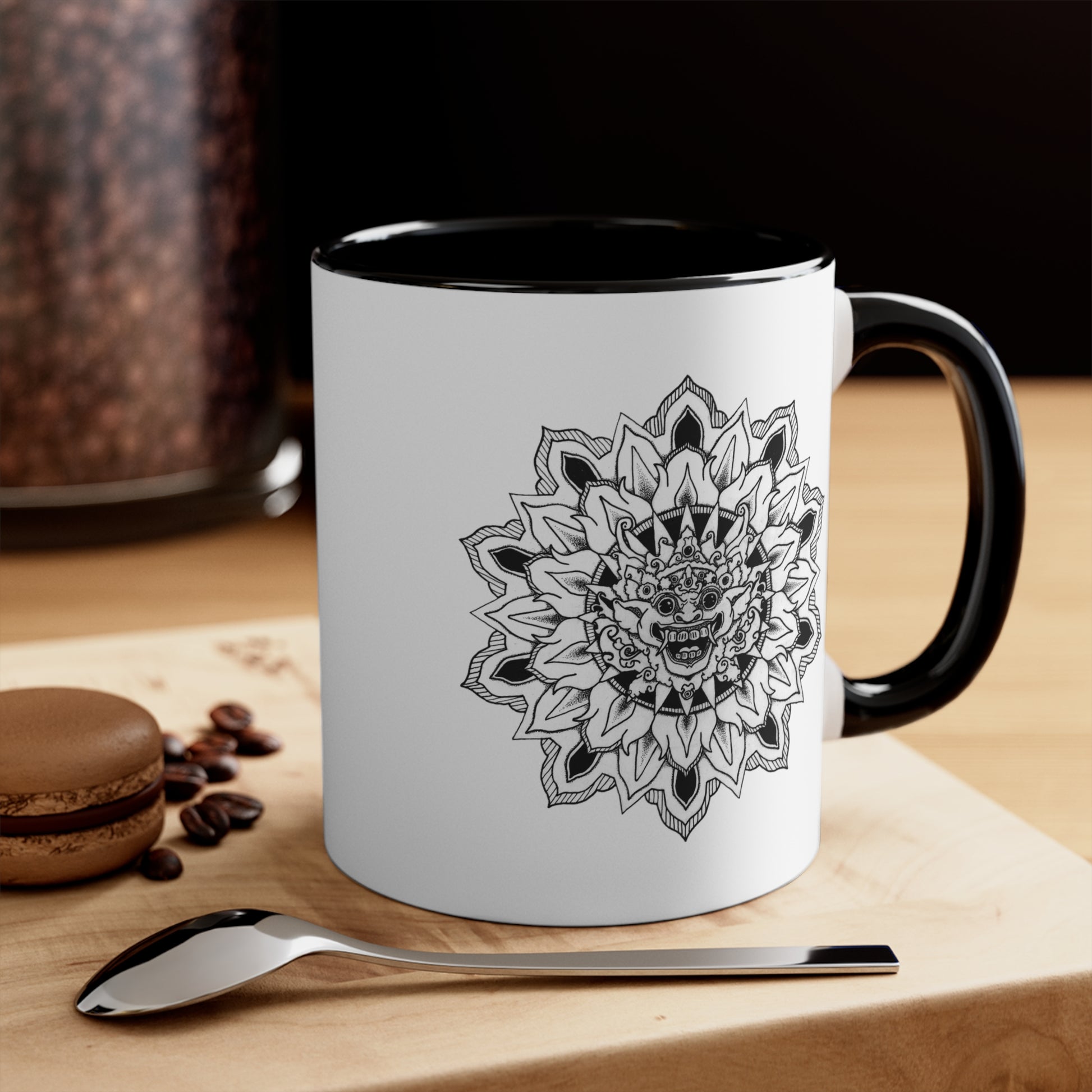 a two-toned white and black 11oz coffee mug with bhoma bali god mandala design on both sides