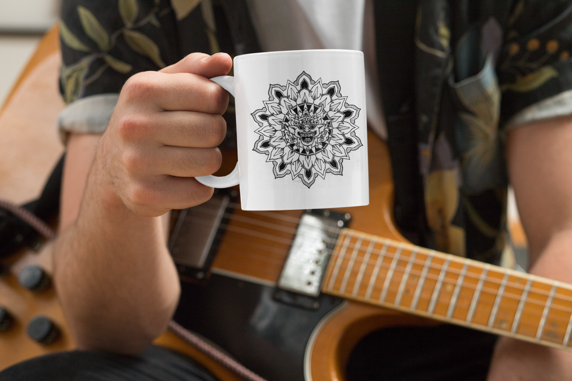 an electric guitar musician holding an 11oz coffee mug with black bhoma bali god mandala design